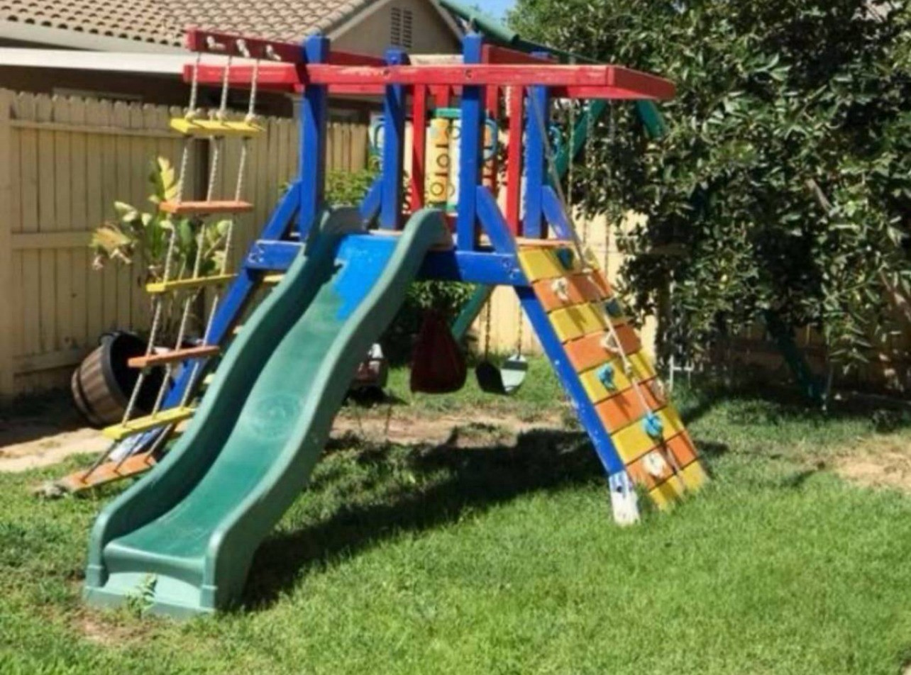 Outdoor daycare playground with swings, climbing wall, and slide